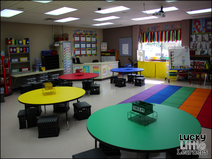 Image showing a bright elementary classroom with colorful center tables, a whole-group rug, and organized learning spaces designed to inspire a new 1st grade teacher.