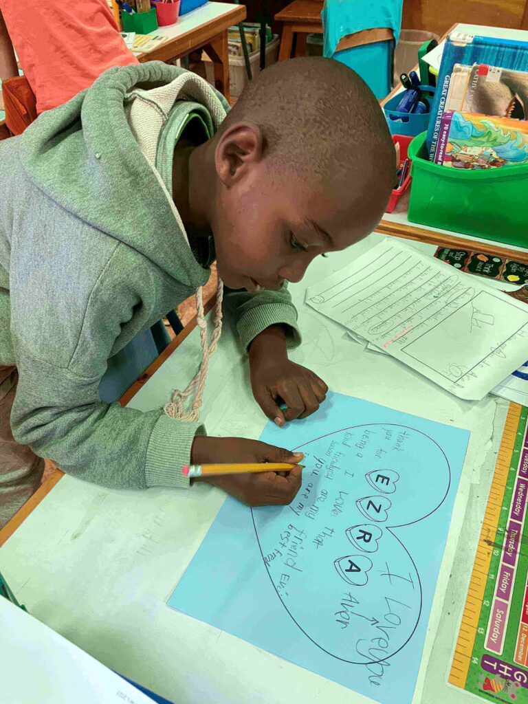 Student writing on heart template during Valentine’s Day read alouds and activities