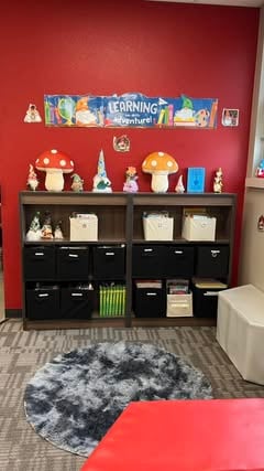 mushrooms and gnome figurines and "learning is an adventure" banner in the classroom library