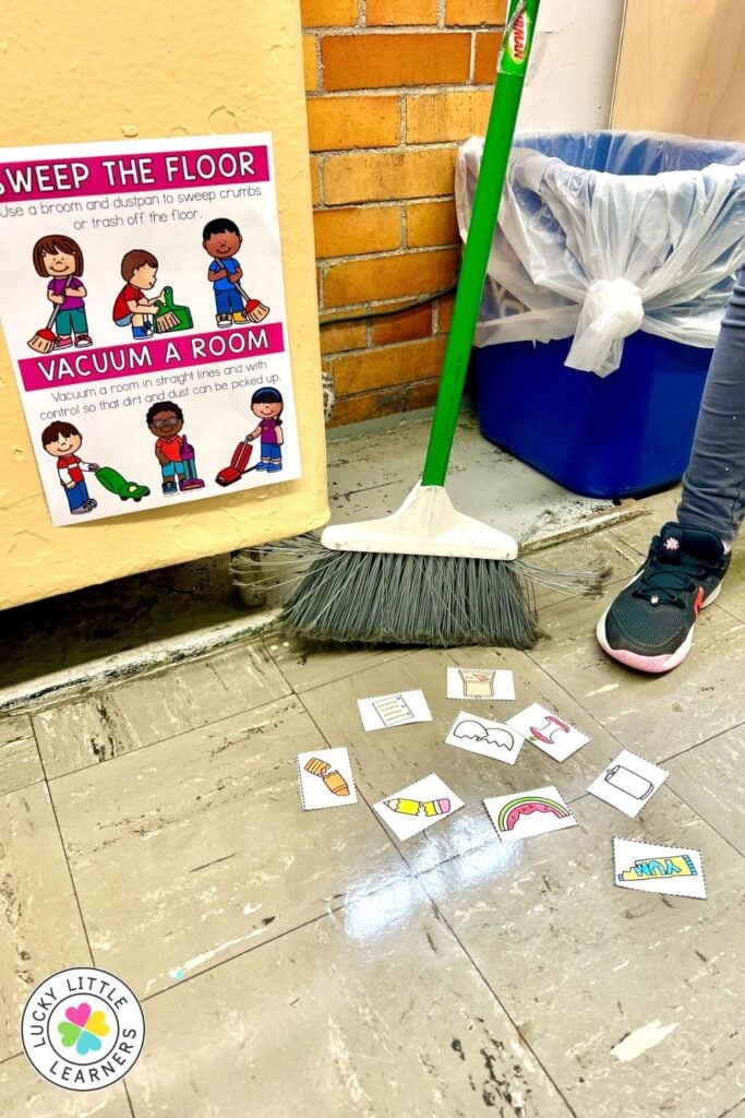 Image showing a classroom chores activity where students practice sweeping the floor using a broom and visual task cards.