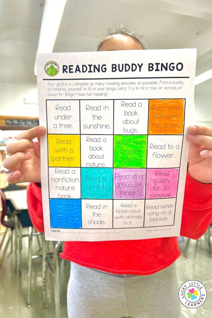 Image showing a student holding a completed Reading Buddy BINGO board used to track progress during buddy reading activities.