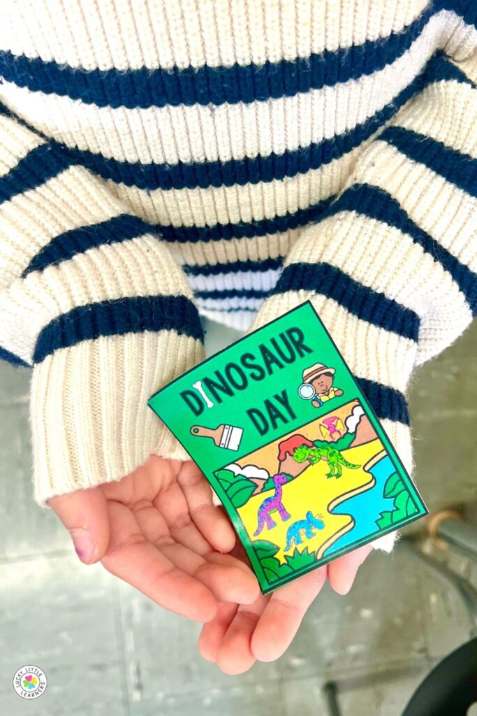 Student holding dinosaur day badge during dinosaur day for first and second grade celebration