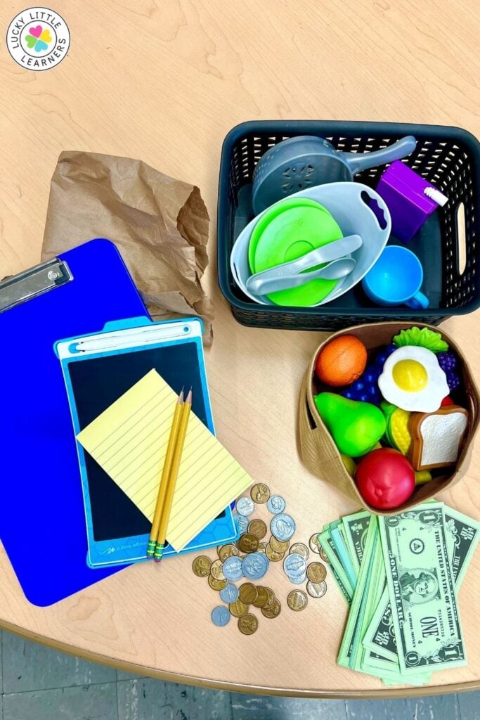 Play kitchen K-2 dramatic play setup with pretend food, money, and cooking supplies