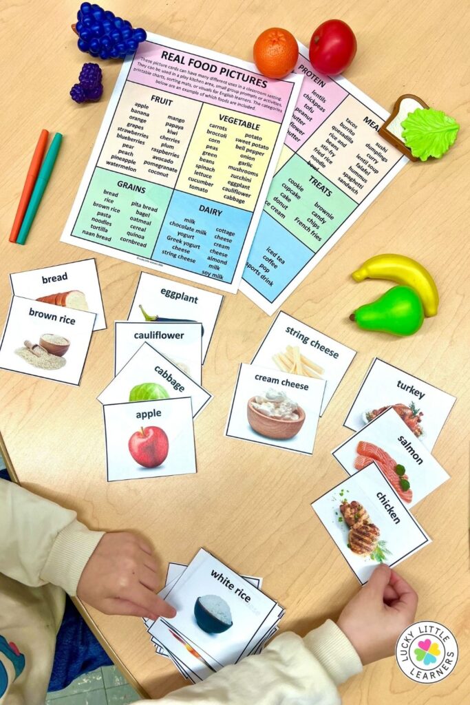 Students sorting food cards by food group during play kitchen K-2 classroom activity
