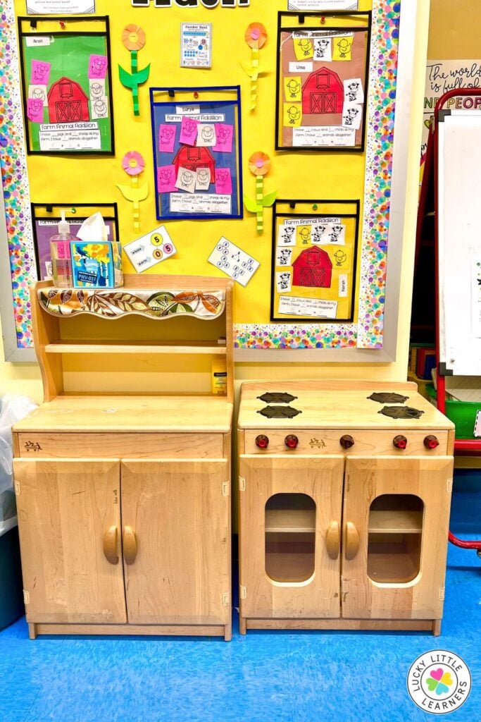 New kindergarten teacher classroom featuring a dramatic play kitchen area and colorful student work display to encourage imaginative learning.