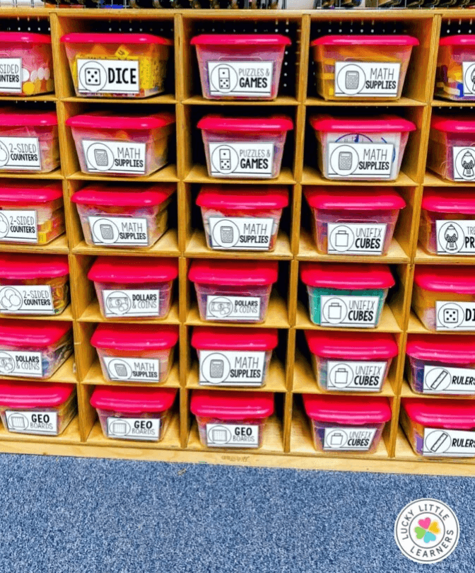 Image showing labeled math supply bins organized on classroom shelves, offering storage ideas for a new 1st grade teacher setting up learning materials and manipulatives.